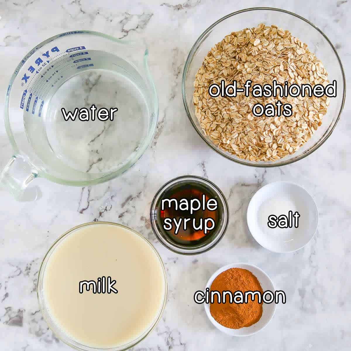 Overhead shot of ingredients - water, old fashioned oats, maple syrup, milk, cinnamon, and salt.