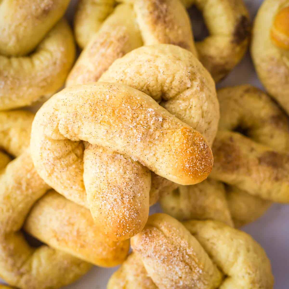 Overhead shot of multiple soft pretzels stacked on each other with a close up of the cinnamon sugar on the top one.