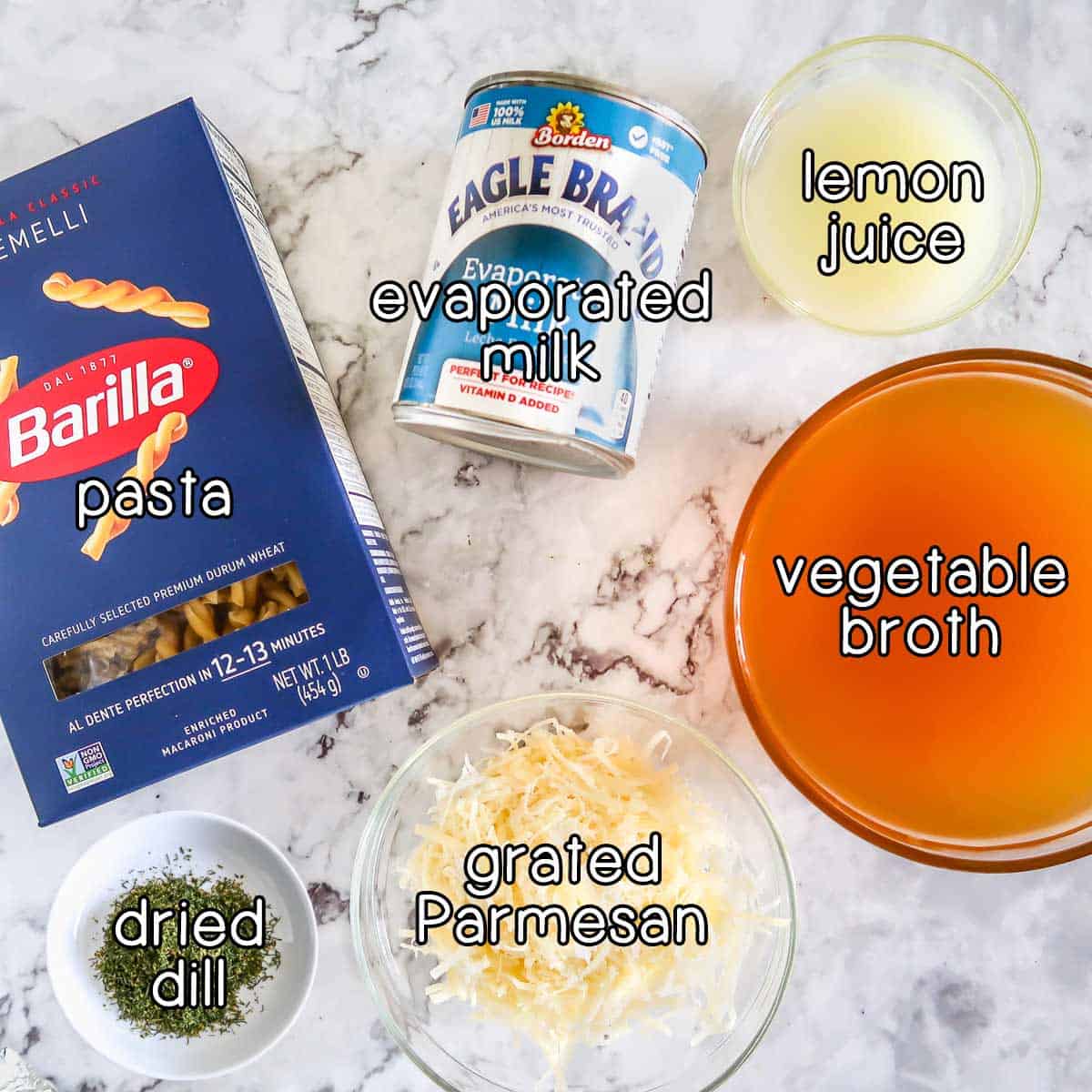 Overhead shot of ingredients - pasta, evaporated milk, lemon juice, vegetable broth, grated parmesan, and dried dill.