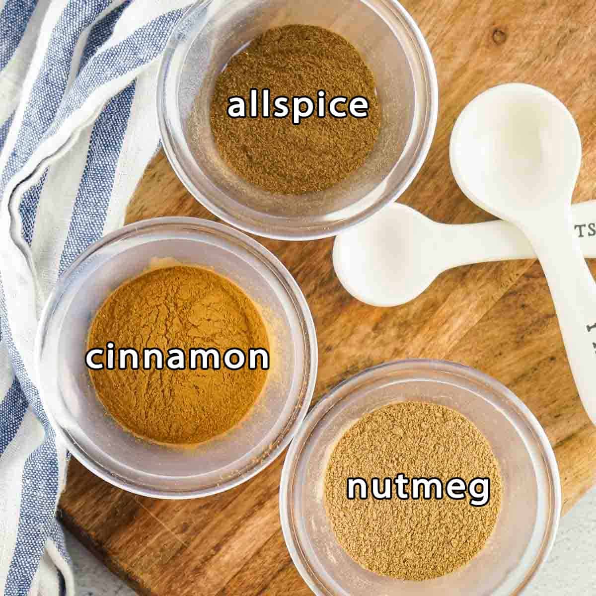 Overhead shot of ingredients - allspice, cinnamon, and nutmeg with measuring spoons on the side.