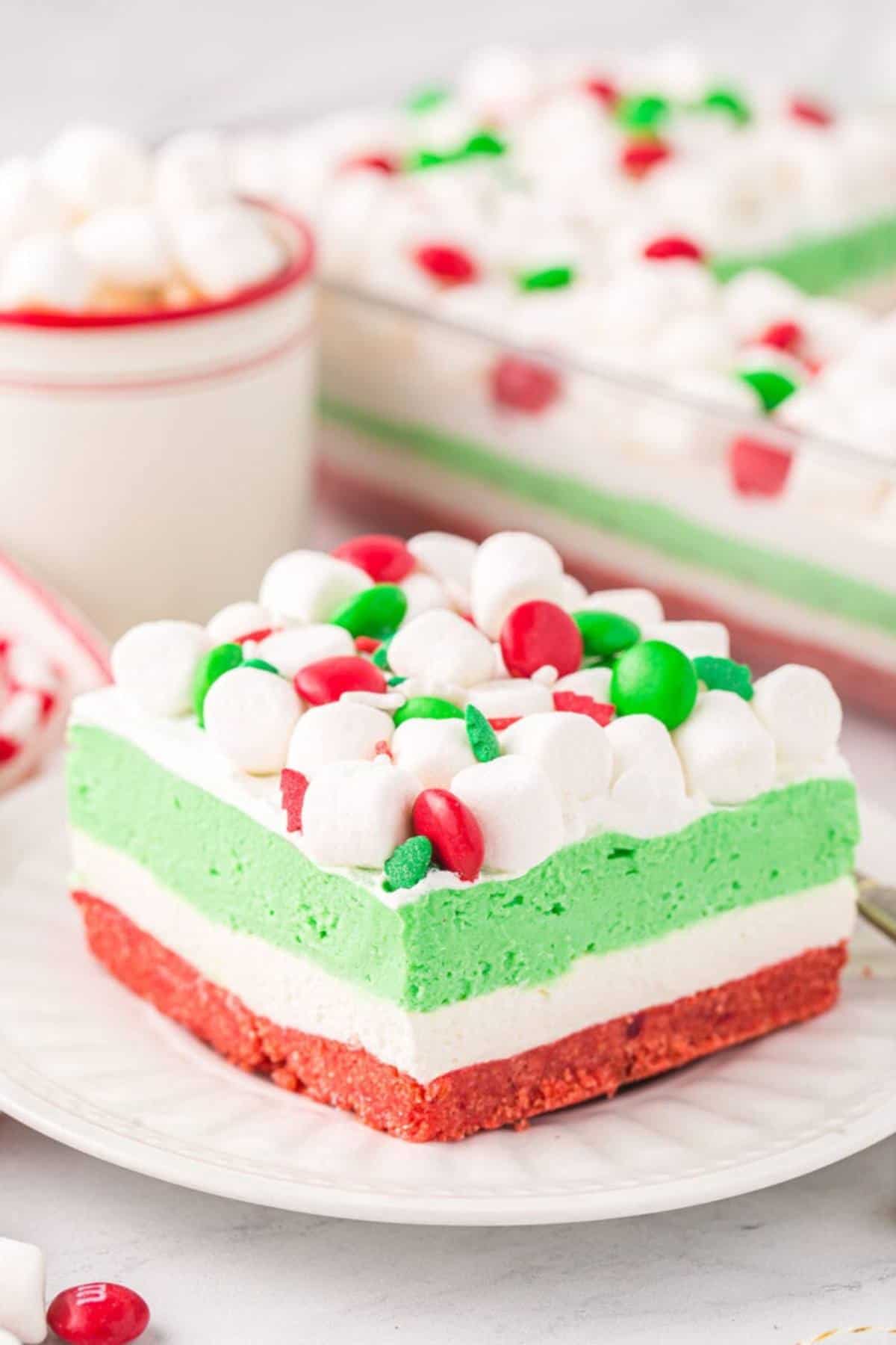 Cake square with red, white, and green layers topped with mini marshmallows and red and green M&Ms.