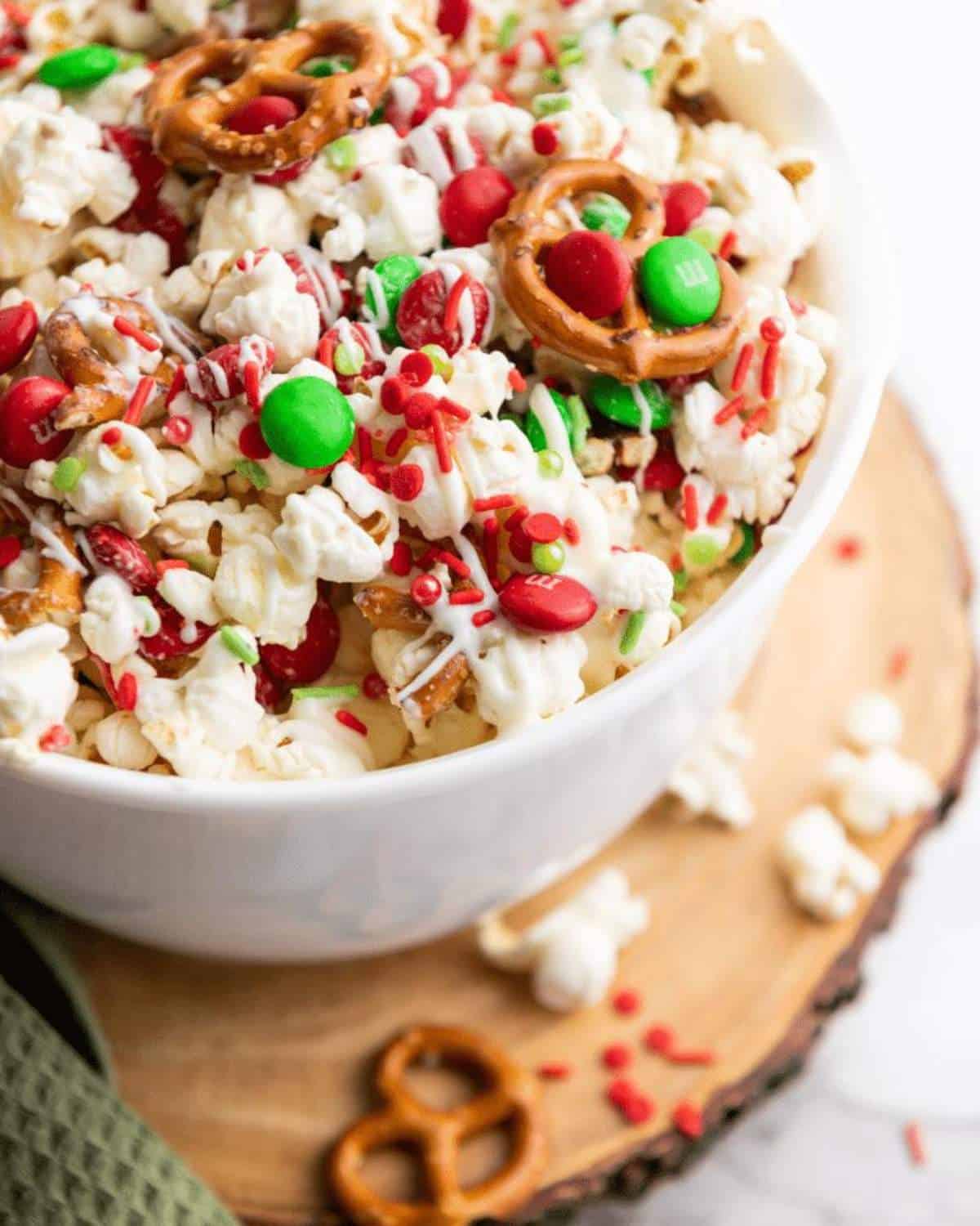 Bowl of popcorn topped with red and green sprinkles and candies.