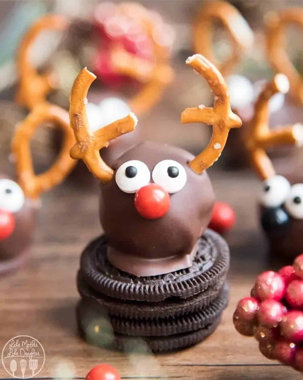 One-inch chocolate ball with googly eyes, a red nose, and pretzel antlers that looks like a reindeer sitting atop an oreo cookie.