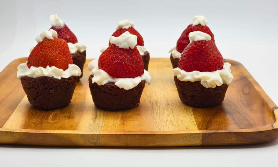  Brownie bites topped with whipped cream and strawberries to look like festive Santa Claus hats.