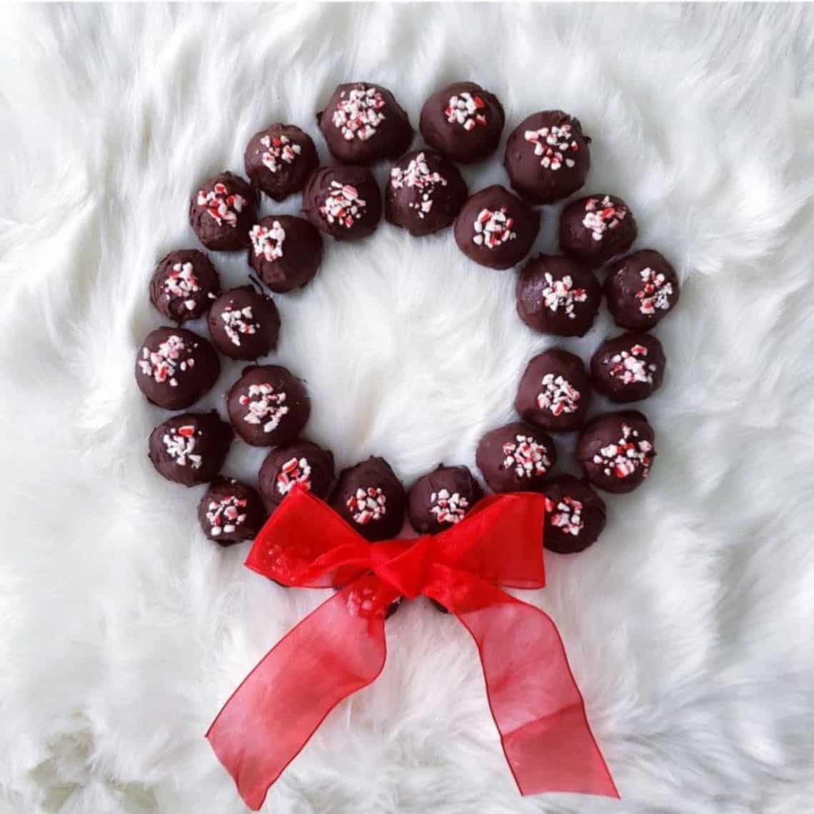Chocolate balls with candy cane topping arranged in wreath shape with a red bow.
