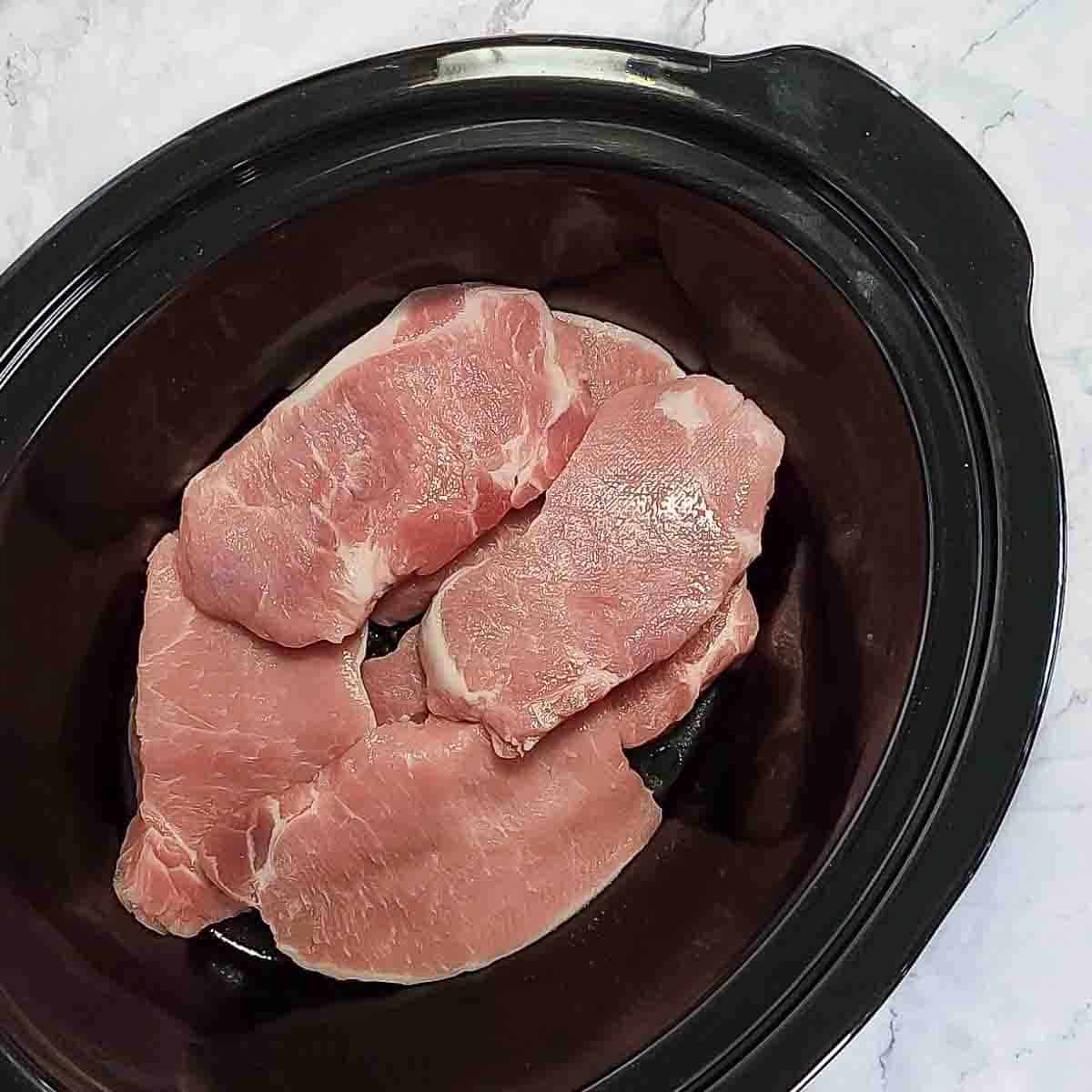 Overhead view of process shot 3 - placing pork chops in the slow cooker.