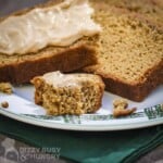Close up shot of two slices and a small piece of ginger loaf with apple butter cream cheese on a white and green plaid plate on a green cloth.