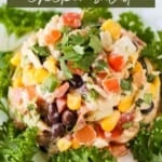 Overhead close up shot of southwest chicken salad garnished with fresh cilantro on a white plate with a fork on the side.