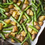 Overhead shot of green beans and potatoes on a sheet pan line with parchment paper.