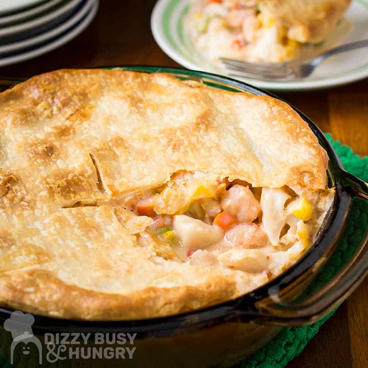Side shot of seafood pot pie with a slice taken out on a green potholder.