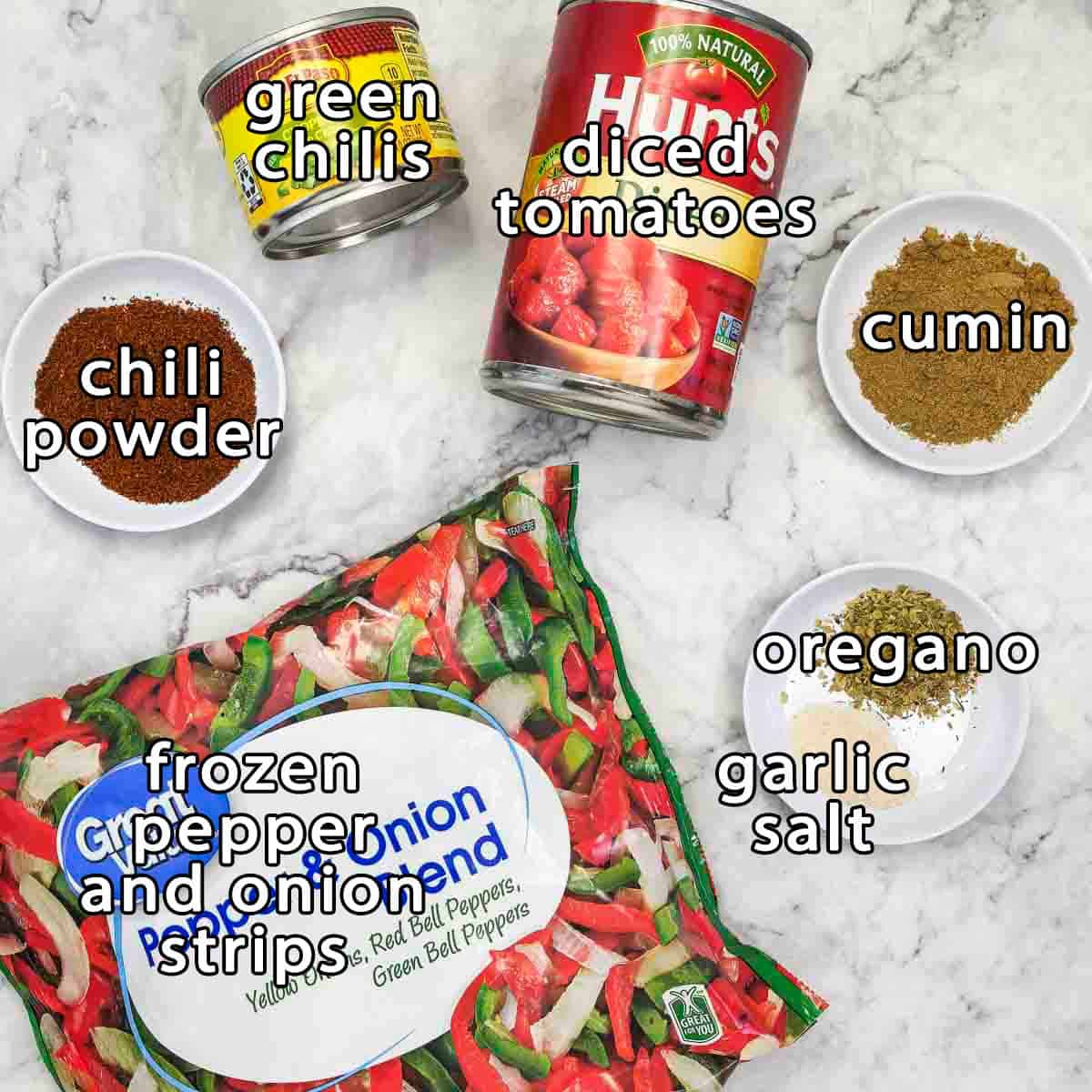 Overhead shot of ingredients - green chilis, diced tomatoes, cumin, chili powder, frozen pepper and onion strips, oregano, and garlic salt.