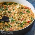 Side close up shot of creamy tomato chicken in a skillet with a spatula on the side.