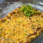 Side shot of crescent roll casserole in a baking dish garnished with fresh herbs on a marble countertop.