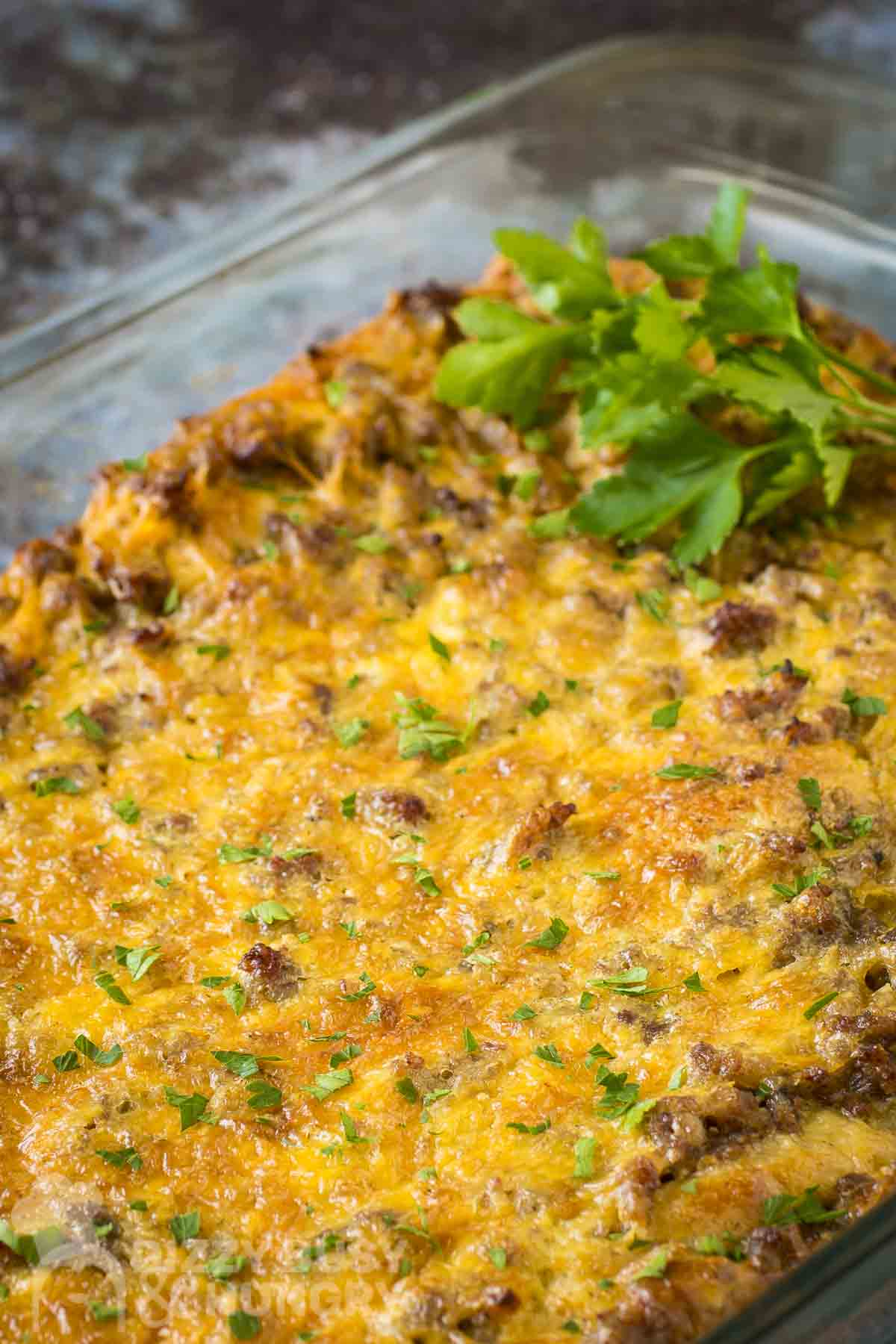 Side shot of crescent roll casserole in a baking dish garnished with fresh herbs on a marble countertop.