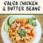 Side shot of mango salsa chicken and butter beans over rice garnished with fresh herbs and lime slices in a white bowl.