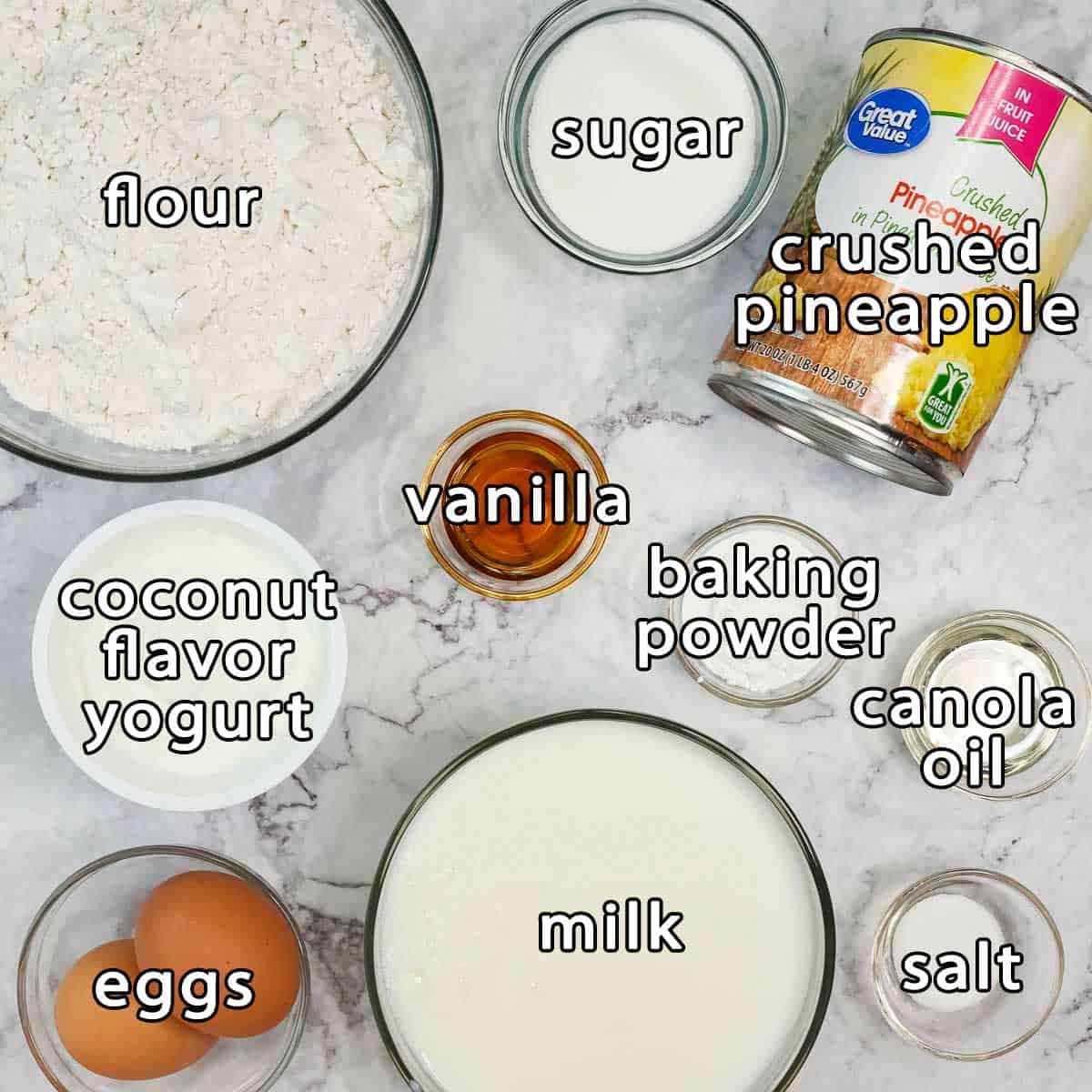 Overhead shot of pineapple pancakes ingredients - flour, sugar, crushed pineapple, vanilla, coconut flavored yogurt, baking powder, canola oil, eggs, milk, and salt.