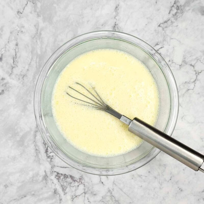 Overhead view of pancakes process shot 2 - in a separate bowl, whisk together the milk, eggs, canola oil, vanilla extract, and yogurt.