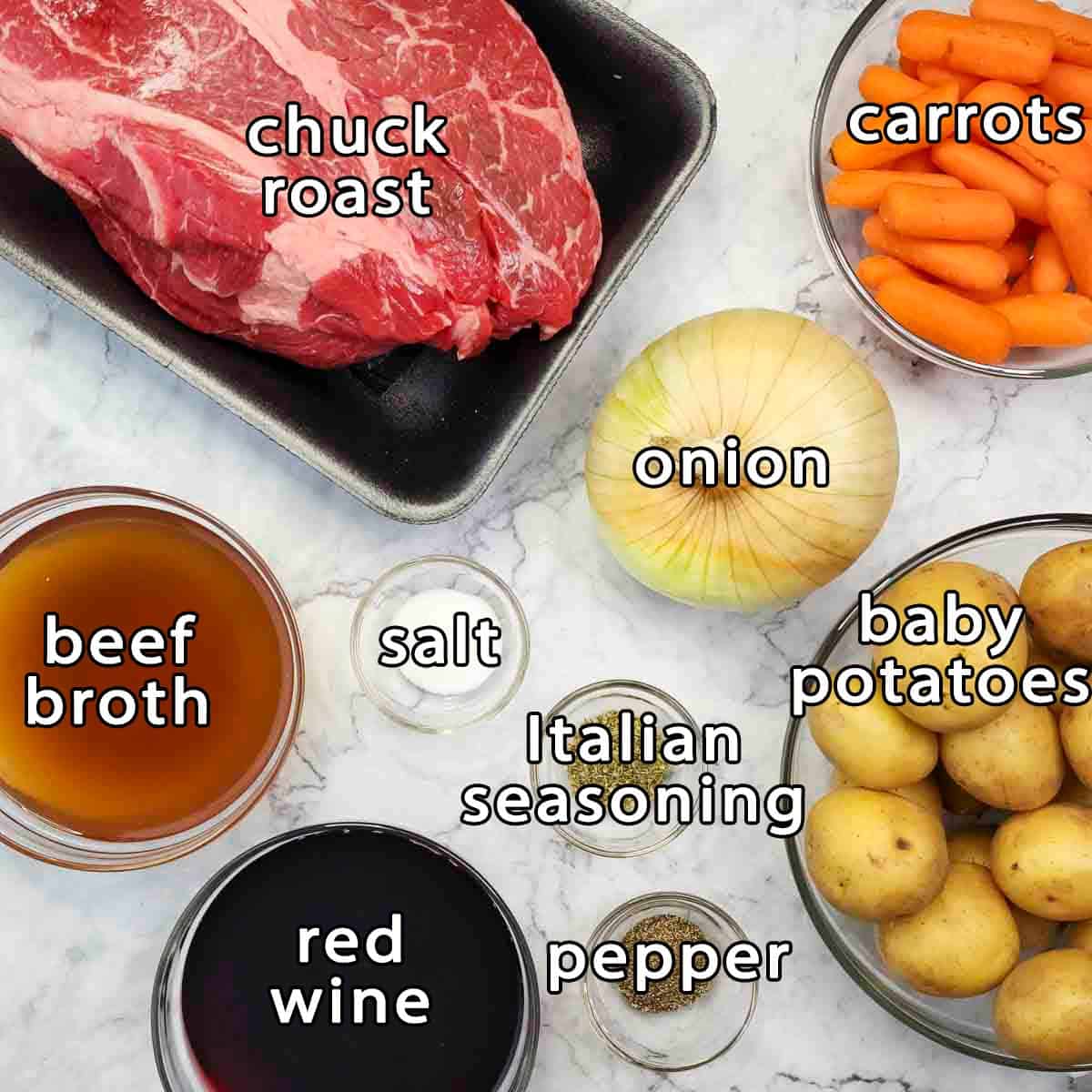 Overhead shot of ingredients - chuck roast, carrots, onion, baby potatoes, beef broth, red wine, salt, pepper, and italian seasoning.