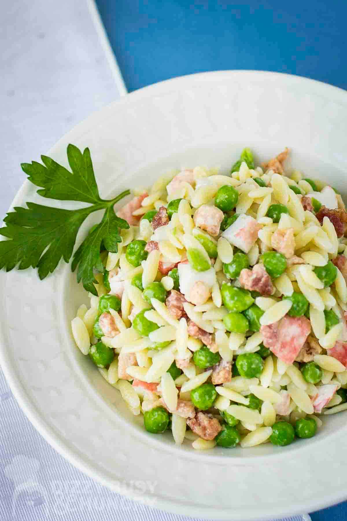 Overhead shot of crab pasta salad in a white bowl garnished with fresh parsley.