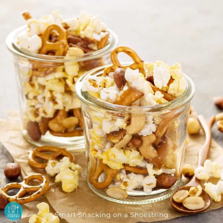 Trail mix including popcorn, pretzels, and peanuts in a glass jar.