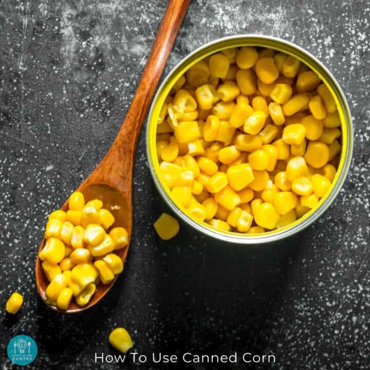 Overhead view of an open can of corn with a wooden spoon to the right holding a bunch of kernals.