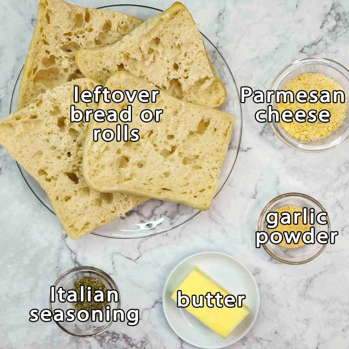 Overhead shot of ingredients - leftover bread or rolls, parmesan cheese, garlic powder, butter, and italian seasoning.