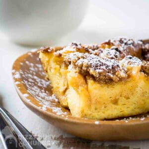 Side shot of brioche french toast on a brown plate sprinkled with powdered sugar.