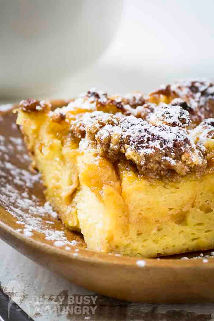Side shot of brioche french toast on a brown plate sprinkled with powdered sugar.