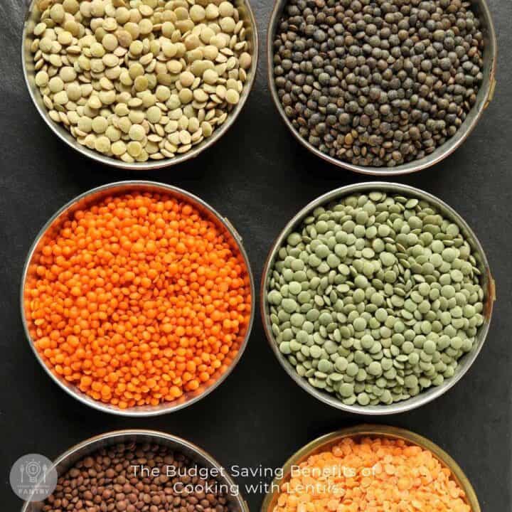 Overhead view of 6 different types of lentils in metal bowls on a slate countertop.