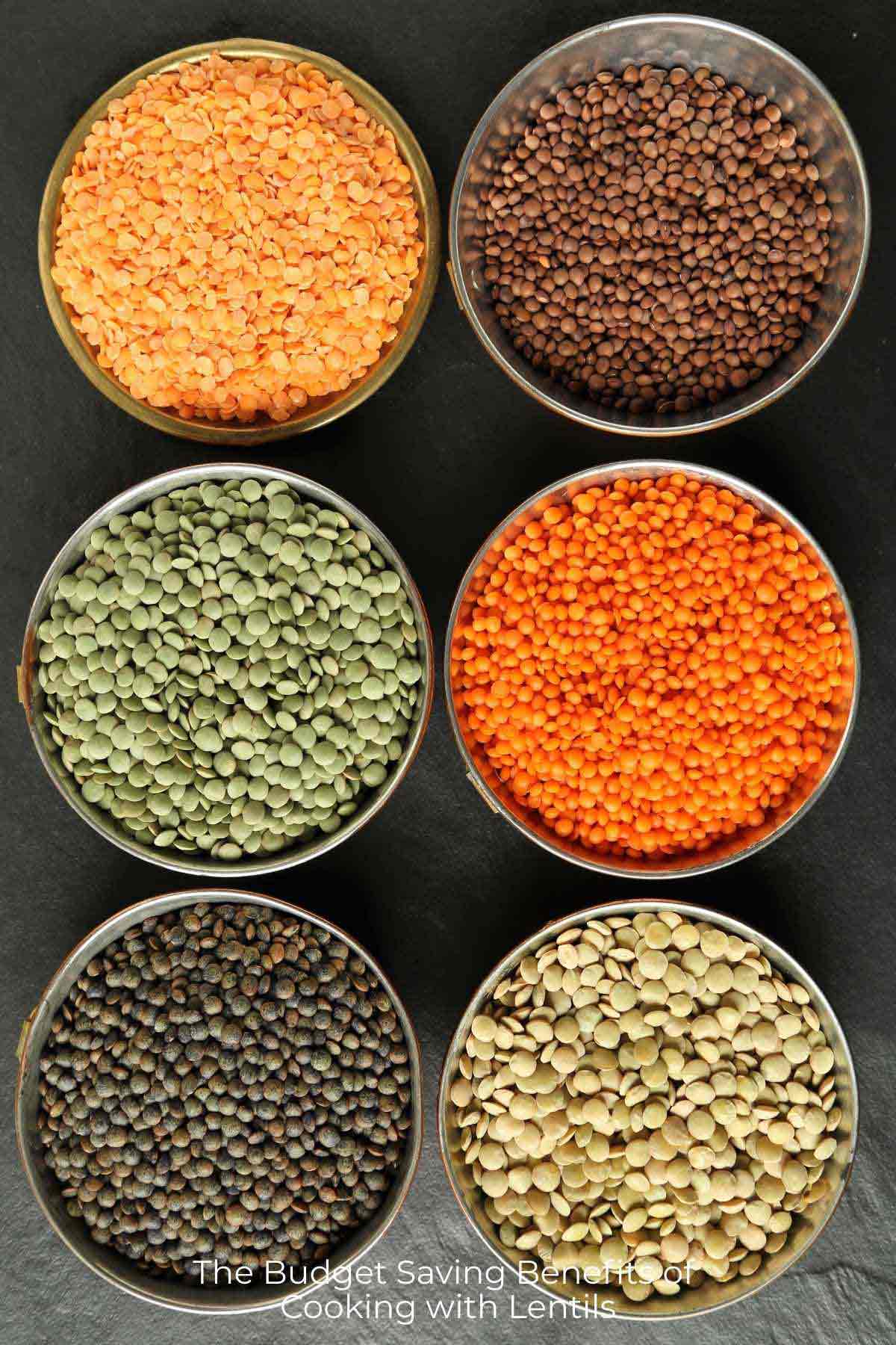 Overhead view of 6 different types of lentils in metal bowls on a slate countertop with text 'Budget Saving Benefits of Cooking With Lentils'.