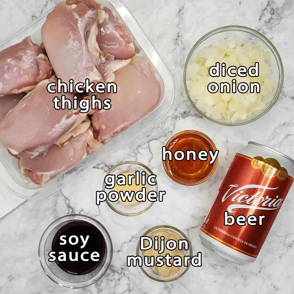 Overhead shot of ingredients - chicken thighs, diced onion, soy sauce, garlic powder, honey, beer, and dijon mustard.