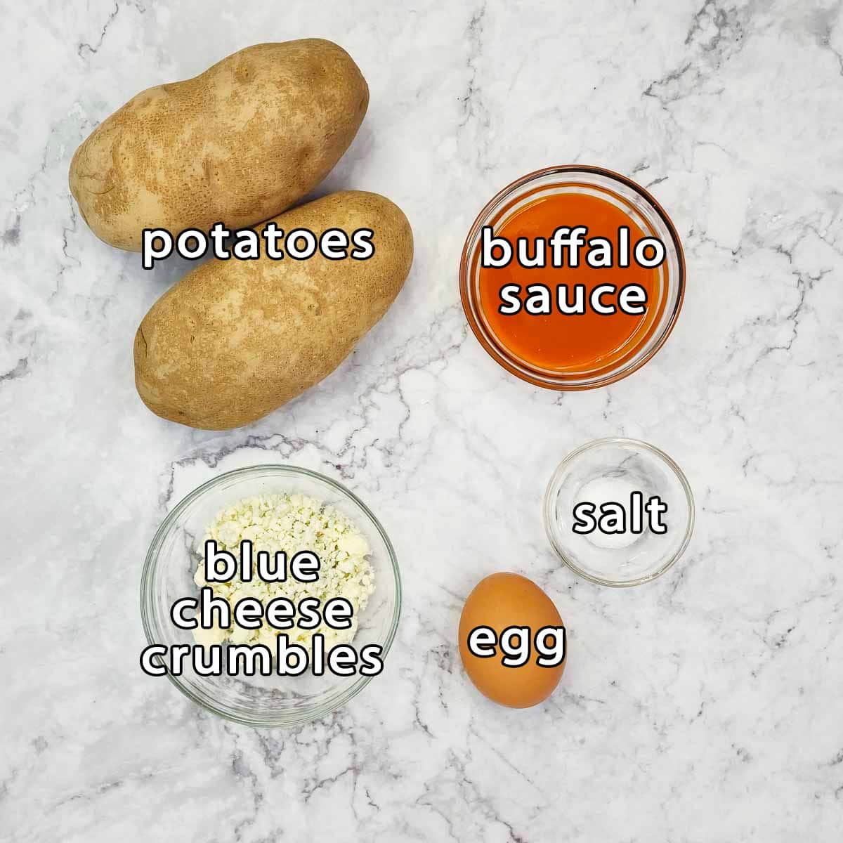 Overhead shot of ingredients - potatoes, buffalo sauce, blue cheese crumbles, egg, and salt.