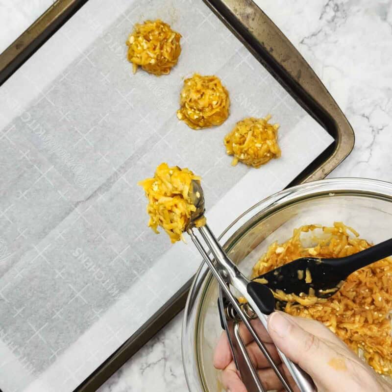 Overhead view of process shot 4 - using a cookie scoop, make balls from the potato mixture and place on a baking sheet lined with parchment paper.