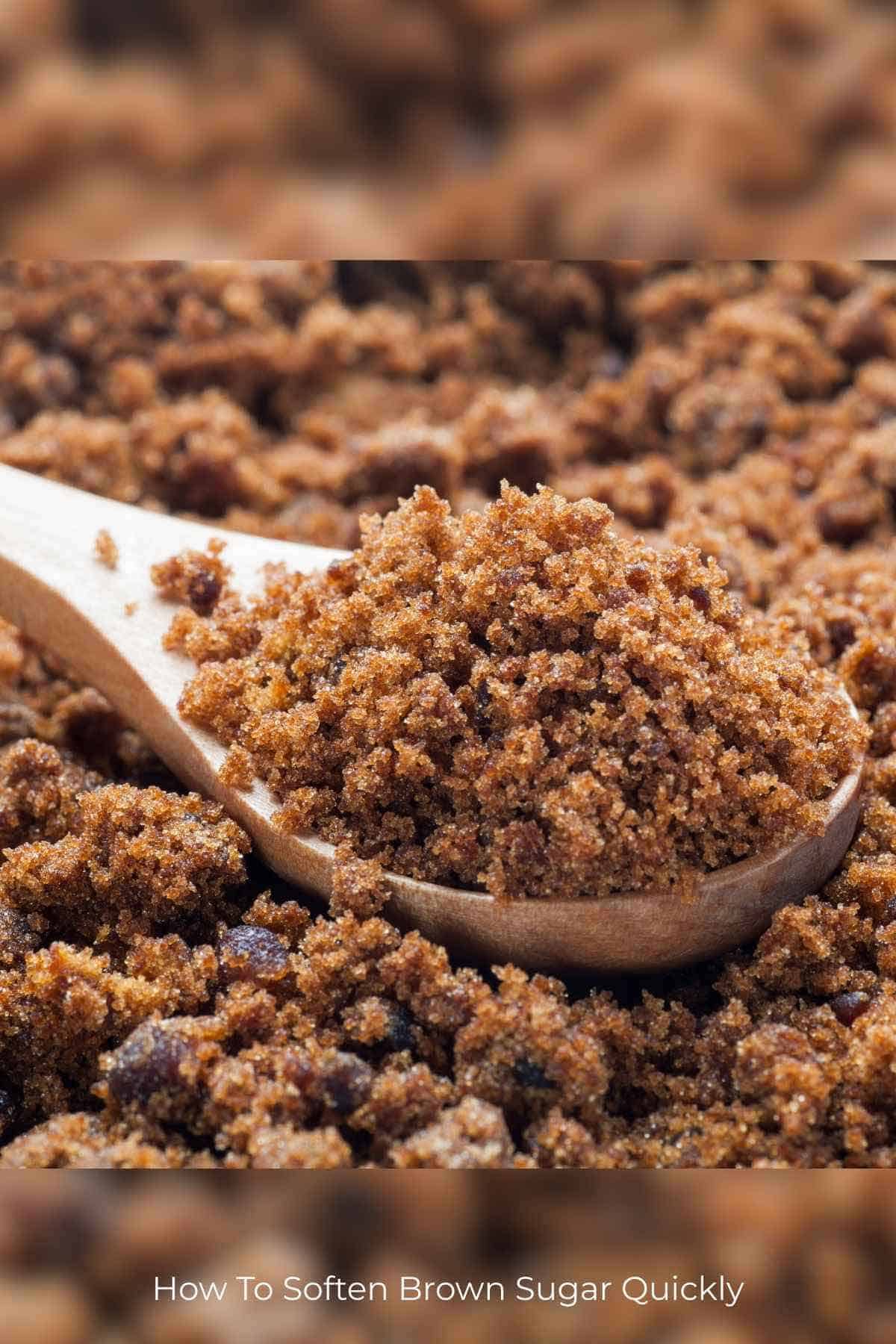 A spoonful of brown sugar in a wooden spoon nestled on a pile of more brown sugar.