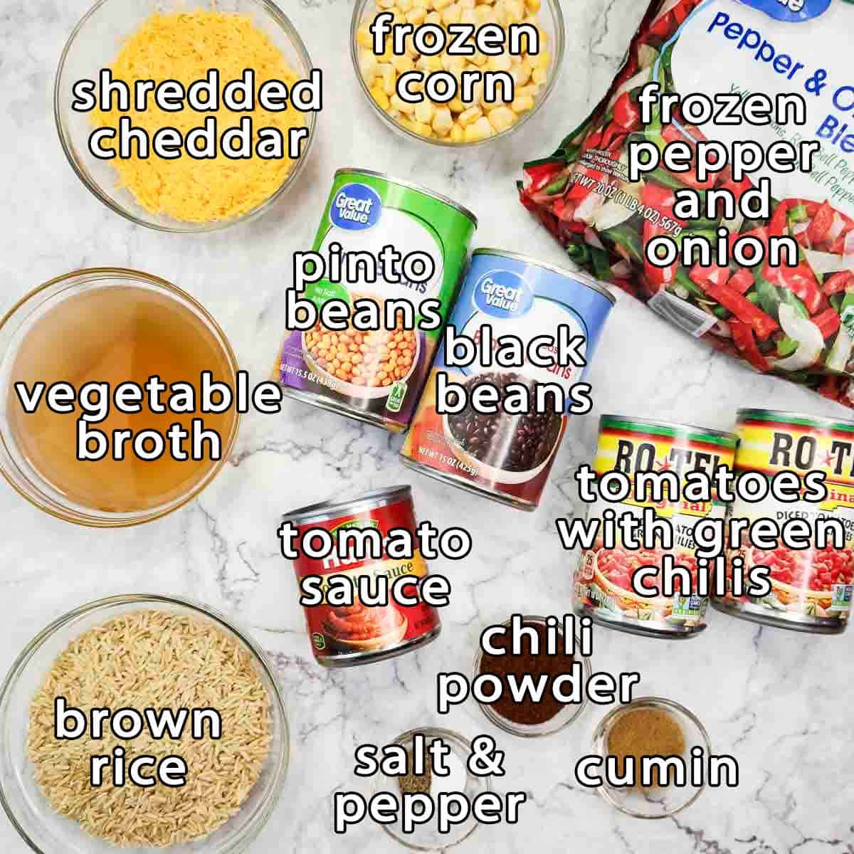 Overhead shot of ingredients - shredded cheddar, frozen corn, frozen pepper and onion, vegetable broth, pinto beans, black beans, tomatoes with green chilis, tomato sauce, brown rice, chili powder, cumin, and salt & pepper.