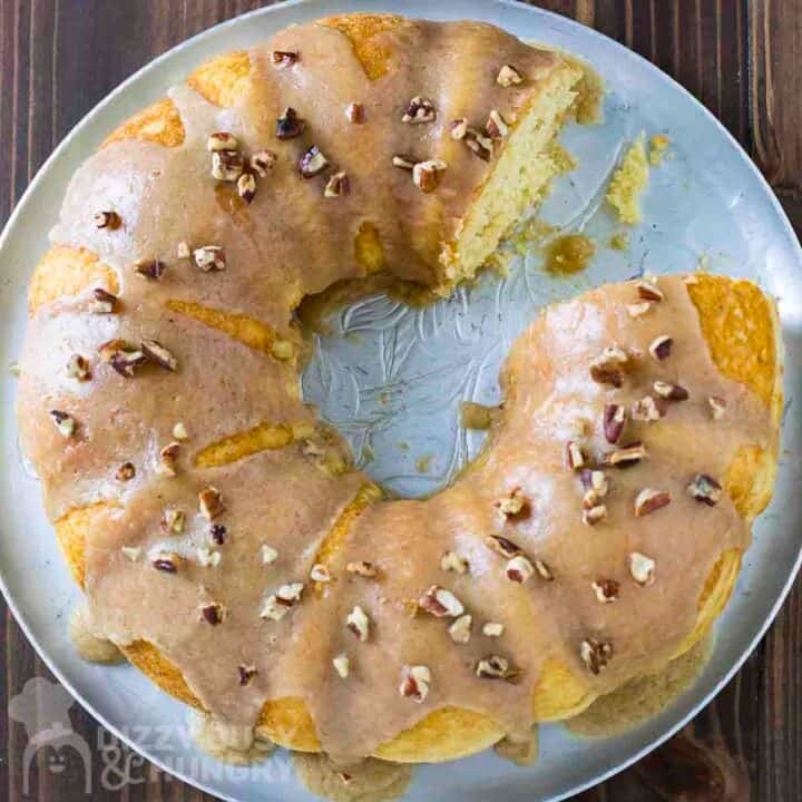 Overhead shot of bundt cake with a piece taken out on a silver serving tray on a wooden table.