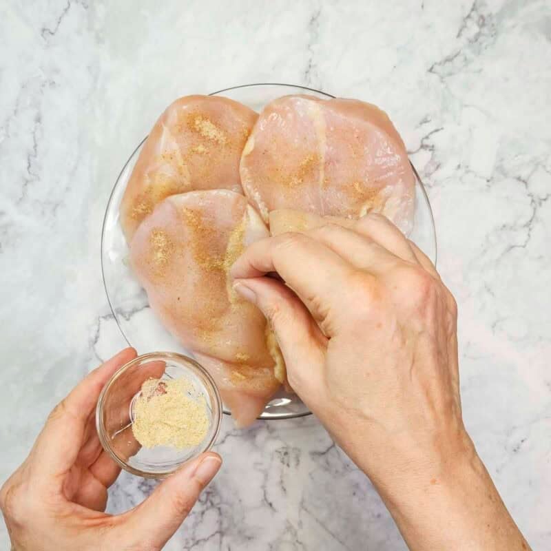 Overhead view of process shot 1 - sprinkle both sides of the chicken with seasoned salt.
