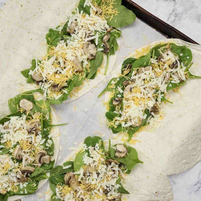 Overhead view of process shot 3 - distribute about half of each of the cheeses then layer the spinach, mushrooms, and the rest of the cheeses.