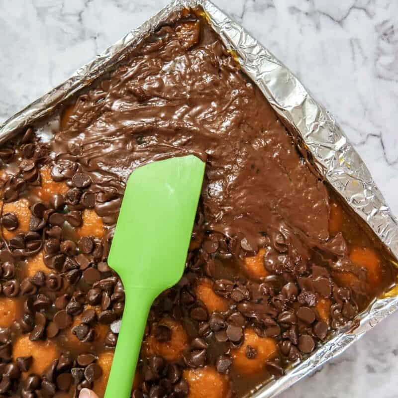 Overhead view of process shot 5 - take the pan out of the oven and sprinkle the chocolate chips on top. When the chips soften, spread them with a spatula.