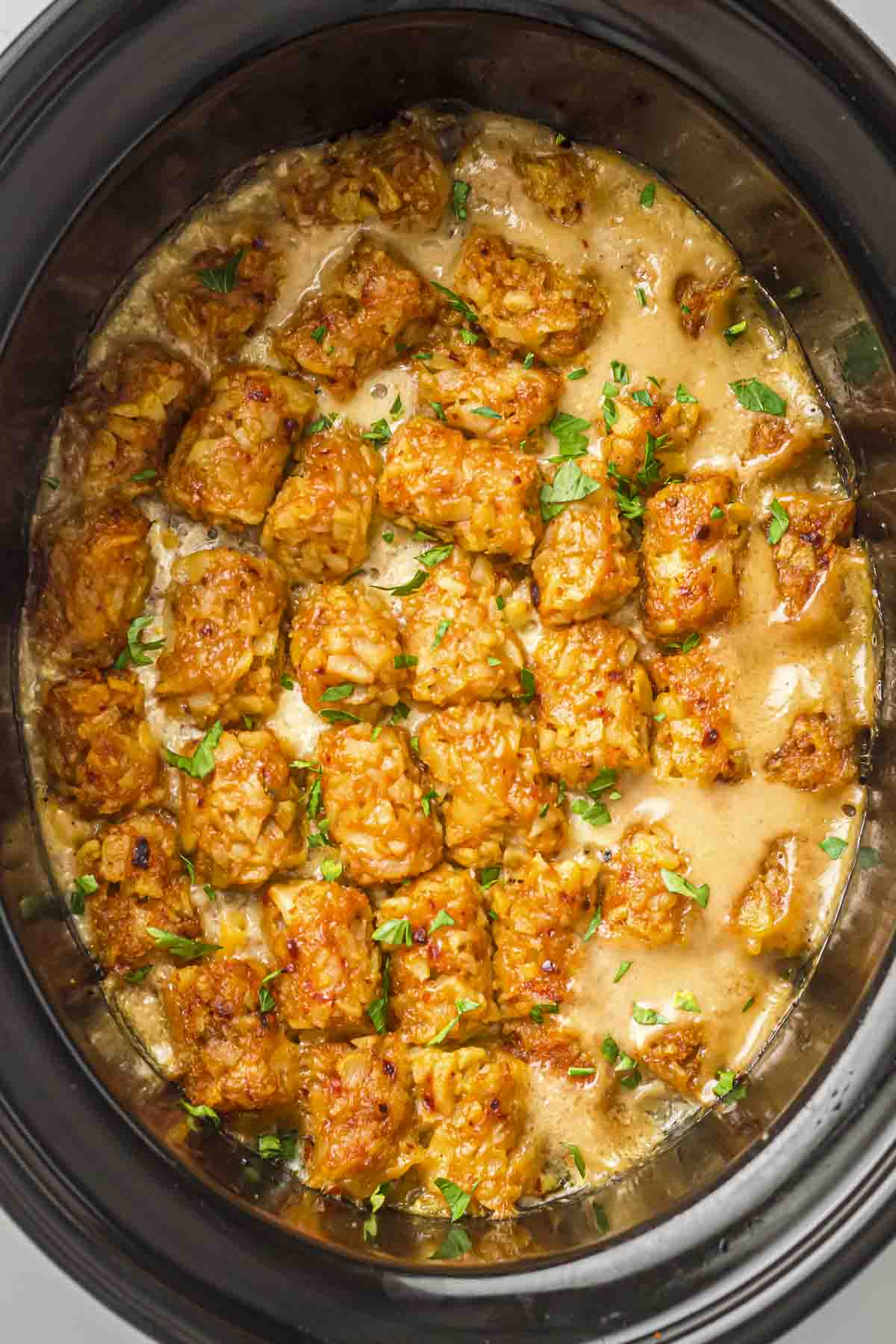 Overhead shot of cowboy casserole in the slow cooker garnished with fresh herbs.
