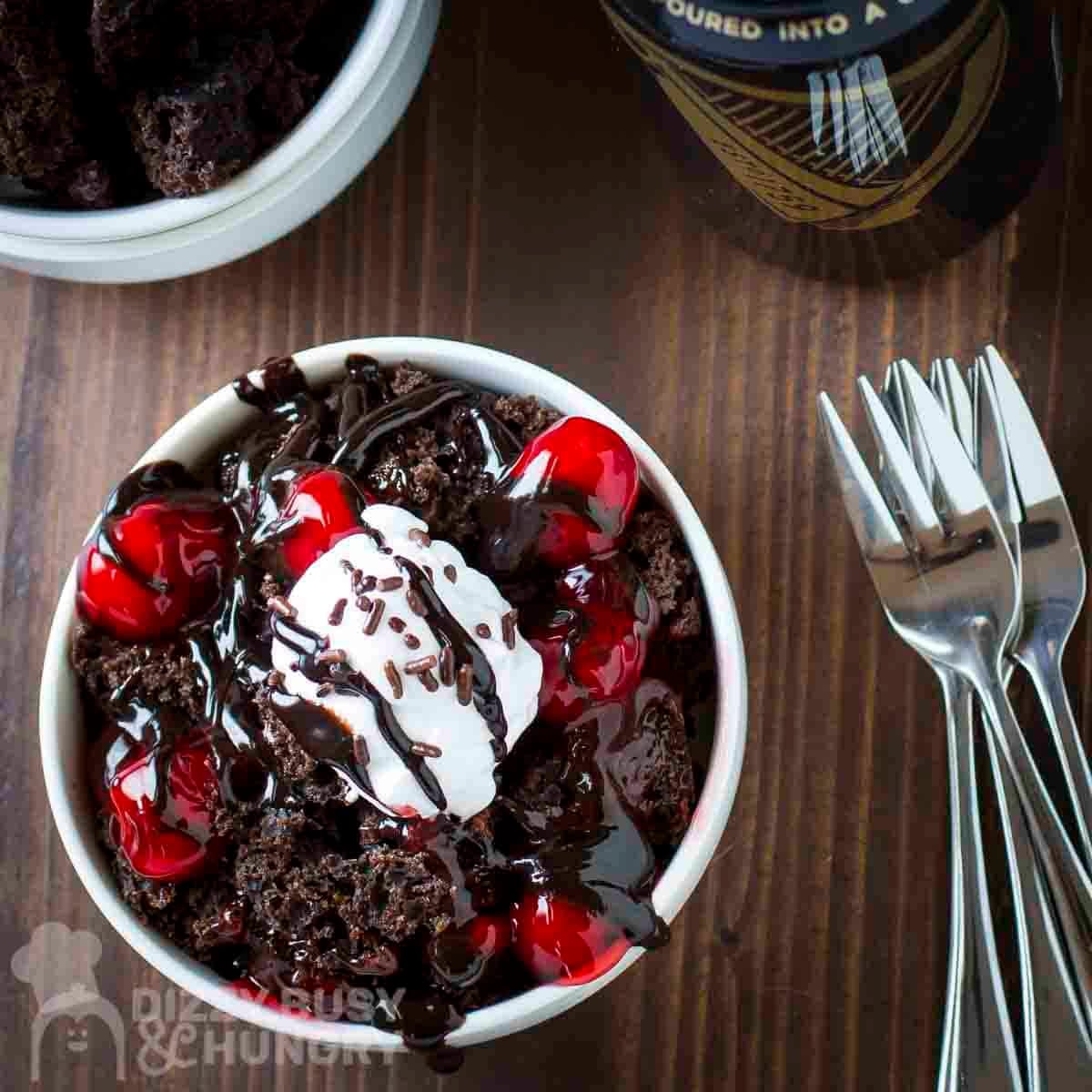 Overhead view of Guinness chocolate cake in a white bowl with forks and a glass in the background.