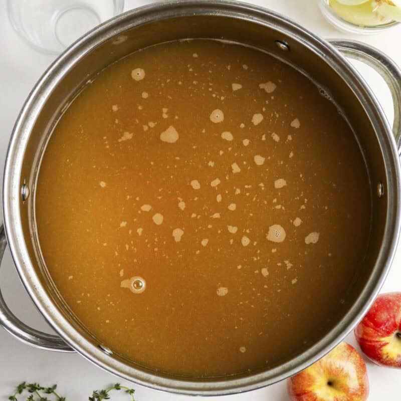 Overhead view of process shot 1 - in a large stockpot, combine apple cider, ½ gallon of the water, kosher salt, and brown sugar. Heat over medium until the salt and sugar dissolve, then remove from heat.