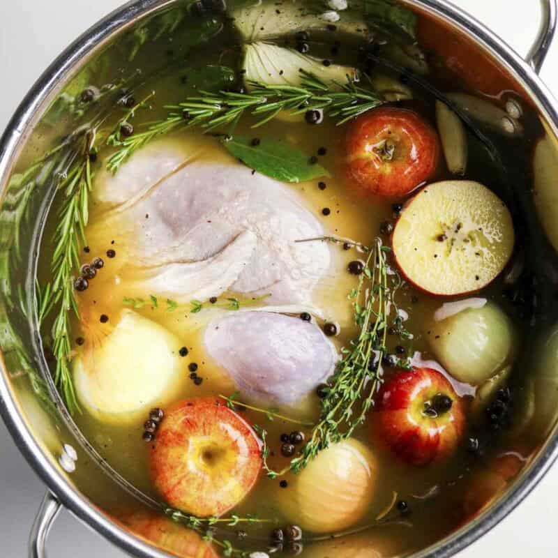 Overhead view of process shot 3 - place your thawed turkey in a large brining bag or clean stockpot. Pour the cooled brine over the turkey, ensuring it is fully submerged.