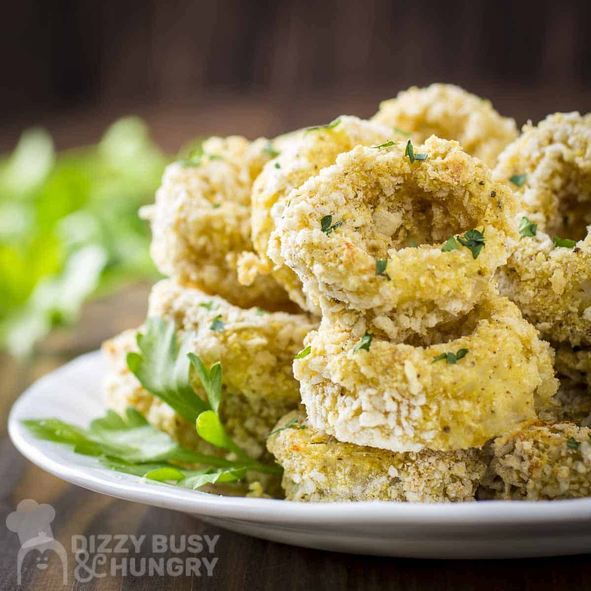 Side view of baked calamari with herbs on a white plate.