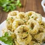 Side view of baked calamari with herbs on a white plate.
