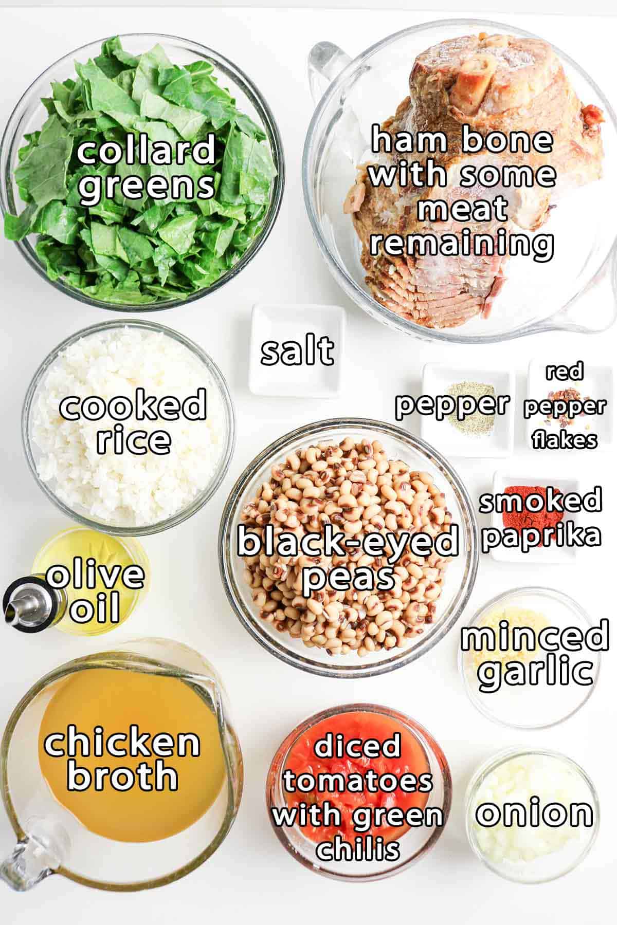 Overhead view of ingredients - ham bone with some meat remaining, collard greens, cooked rice, black-eyed peas, olive oil, chicken broth, diced tomatoes with green chilis, onion, minced garlic, smoked paprika, red pepper flakes, salt, and pepper.