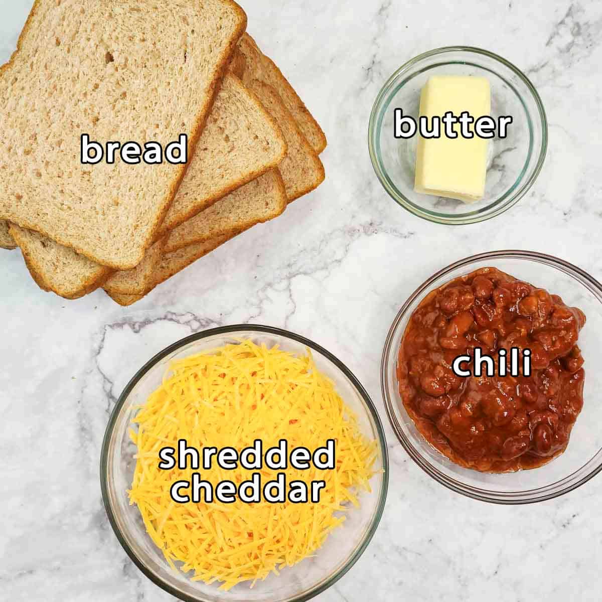 Overhead view of ingredients - bread, butter, shredded cheddar, and chili.
