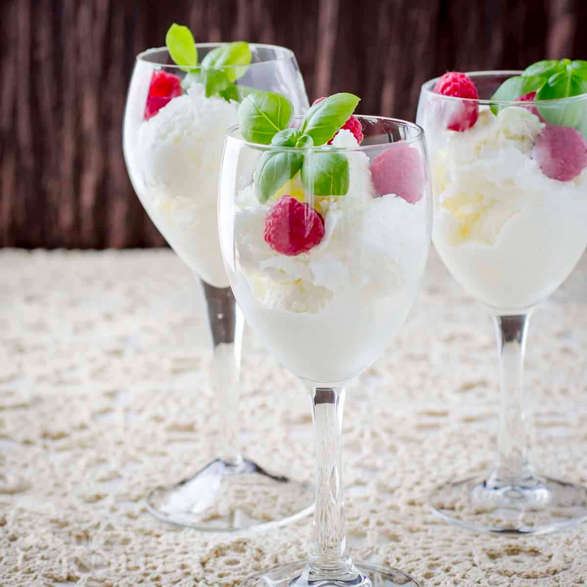 Side shot of three wine glasses with moscato ice cream garnished with raspberries and fresh mint.