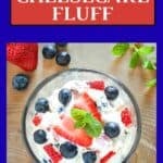 Overhead shot of a small glass bowl filled with cheesecake fluff topped with fresh blueberries and strawberries and fresh basil with more fresh fruits in the background.