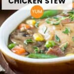 Side angled shot of chicken stew garnished with fresh thyme in a white oval bowl on a wooden surface.